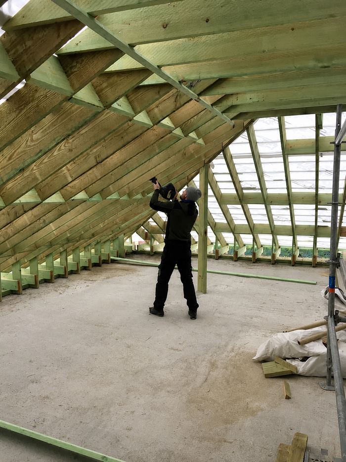 Charpentier fixant les chevrons d'une toiture en construction